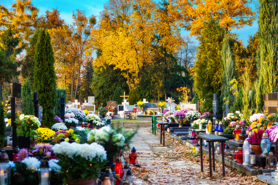 Jesienny cmentarz, groby przyozdobione kwiatami i zniczami